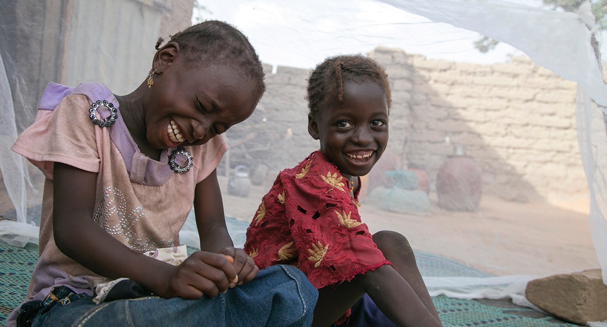 Mariama and her sister, Balkissa Abdou, sit under their mosquito net in Niger. The girls also received medicine to prevent malaria. Photo by Michael Stulman/CRS